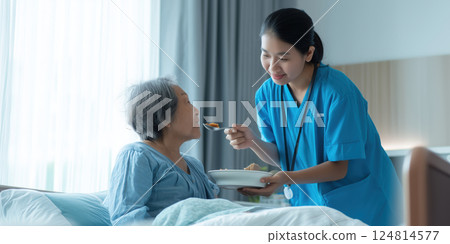 caring healthcare professional in blue uniform assists elderly patient in bed 124814577