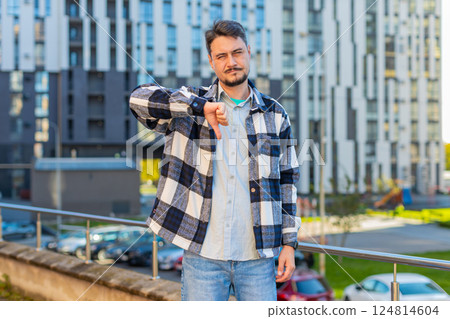 Upset mature Caucasian man tourist showing thumb down expressing discontent on downtown city street Upset mature Caucasian man tourist showing thumb down expressing discontent on downtown city street 124814604