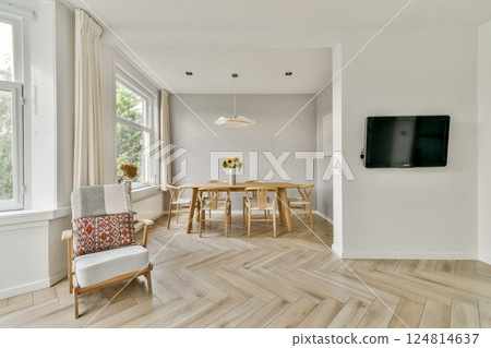 A contemporary dining area featuring an inviting wooden table, stylish chairs, and natural lighting streaming through large windows, creating a serene atmosphere. A contemporary dining area featuring an inviting wooden table, stylish chairs, and natural lighting streaming through large windows, creating a serene atmosphere. 124814637