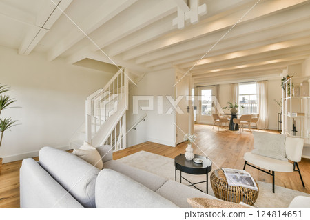 A stylish modern interior featuring a bright living room with a cozy sofa and a staircase leading to an upper level, blending comfort and elegance. A stylish modern interior featuring a bright living room with a cozy sofa and a staircase leading to an upper level, blending comfort and elegance. 124814651