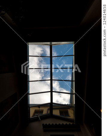 Open skylight window showing blue sky and clouds in prague Open skylight window showing blue sky and clouds in prague 124814658