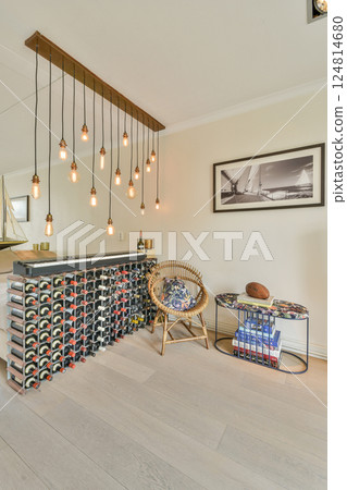 A stylish interior featuring elegant lighting fixtures, a wine rack, comfortable seating, and decorative elements, creating an inviting and modern atmosphere. 124814680