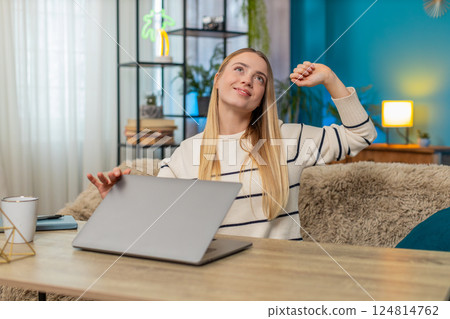 Caucasian young adult woman ending remote workday on sofa at table, smiling, feeling relief indoors Caucasian young adult woman ending remote workday on sofa at table, smiling, feeling relief indoors 124814762