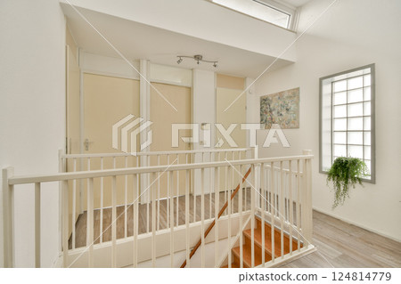 A bright and airy interior showcasing a staircase, featuring wooden steps and a large window that allows natural light to illuminate the space. 124814779