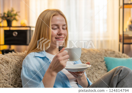 Young woman drinking morning warm coffee at home, sip, refreshed look, relaxed energy, gold sunlight 124814794