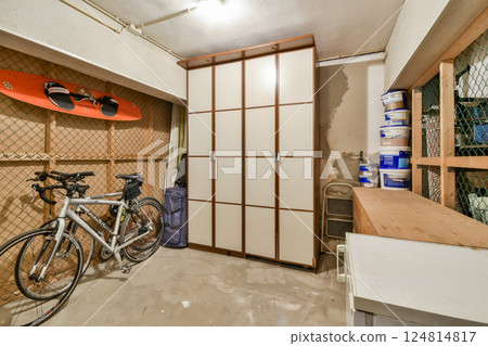 A well-arranged indoor storage area featuring a bicycle, shelving unit, and kayak, ideal for maximizing space and functionality. A well-arranged indoor storage area featuring a bicycle, shelving unit, and kayak, ideal for maximizing space and functionality. 124814817