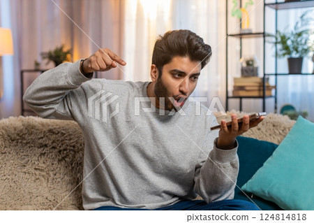 Man talking on phone via speaker mode gesturing emotionally and looking irritated during an argument 124814818