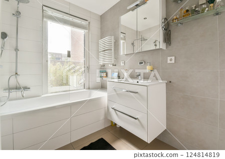 A sleek and contemporary bathroom featuring a bathtub, modern fixtures, and natural light streaming through the window, creating a serene atmosphere. A sleek and contemporary bathroom featuring a bathtub, modern fixtures, and natural light streaming through the window, creating a serene atmosphere. 124814819