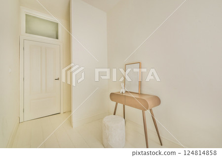 An elegant and airy interior featuring a sleek table and a mirror, showcasing a minimalist aesthetic with neutral colors and simple lines. 124814858
