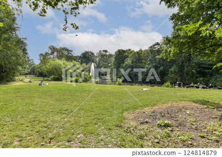 A peaceful park scene featuring lush greenery, a tranquil pond, and a fountain, perfect for relaxation and outdoor enjoyment. A peaceful park scene featuring lush greenery, a tranquil pond, and a fountain, perfect for relaxation and outdoor enjoyment. 124814879
