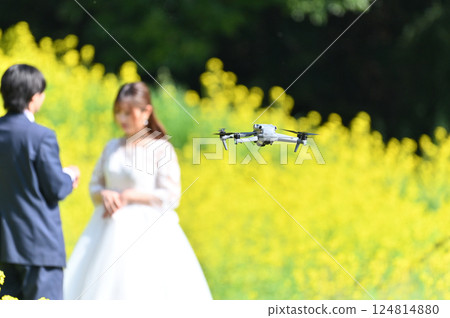 A field of rapeseed flowers in full bloom. A couple photographed with a drone. Wedding photography. A field of rapeseed flowers in full bloom. A couple photographed with a drone. Wedding photography. 124814880