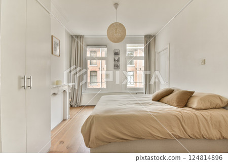 A chic and serene modern bedroom featuring a neutral color palette, soft bedding, natural light, and minimalist decor elements that create a calming atmosphere. 124814896
