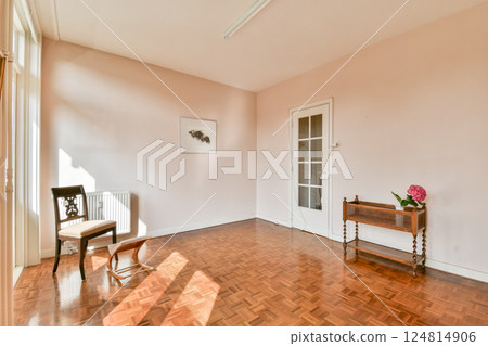 A bright, minimalist interior featuring a wooden floor, a single chair, and subtle decor elements that emphasize spaciousness and natural light. A bright, minimalist interior featuring a wooden floor, a single chair, and subtle decor elements that emphasize spaciousness and natural light. 124814906