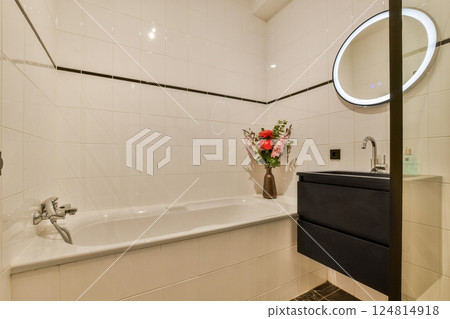 A sleek bathroom featuring a spacious bathtub, stylish sink, and elegant floral arrangement, emphasizing contemporary design and functionality. 124814918
