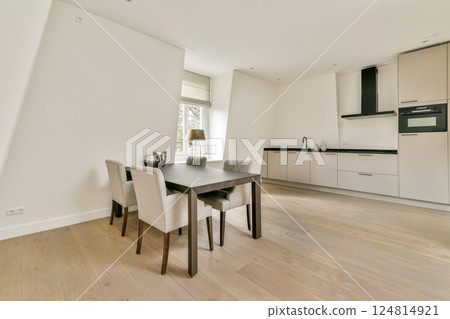 A stylish modern kitchen featuring sleek cabinetry, a dining table, and minimalist decor, creating an inviting and functional space for cooking and dining. A stylish modern kitchen featuring sleek cabinetry, a dining table, and minimalist decor, creating an inviting and functional space for cooking and dining. 124814921