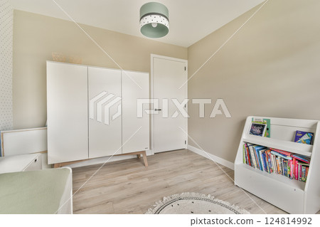 A stylish modern room featuring a sleek white cabinet, a cozy reading nook, and gentle natural light enhancing the warm tones of the walls. 124814992