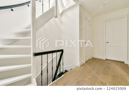 A clean and modern staircase leads to a bright hallway featuring minimalist decor. The light wood flooring complements the subtle white walls. A clean and modern staircase leads to a bright hallway featuring minimalist decor. The light wood flooring complements the subtle white walls. 124815009