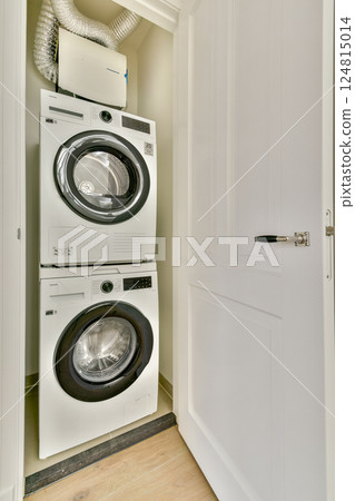 A compact and efficient laundry room featuring a stacked washer and dryer unit, designed for optimal space utilization and convenience. A compact and efficient laundry room featuring a stacked washer and dryer unit, designed for optimal space utilization and convenience. 124815014