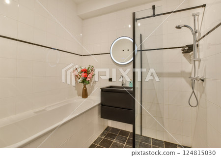 Stylish and contemporary bathroom featuring a shower, bathtub, and a modern mirrored sink, enhanced by a vibrant floral arrangement. 124815030