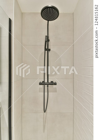 A sleek modern shower with a stylish black shower head and minimalist design, featuring smooth tiles and a contemporary aesthetic, perfect for upscale bathrooms. 124815162