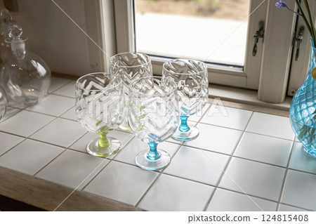 Stylish handmade empty fine wine glasses on the table by the window 124815408