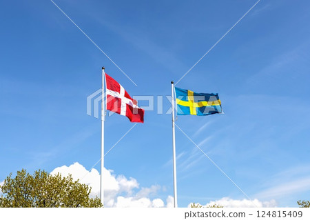 Denmark and Sweden flags against blue sky 124815409
