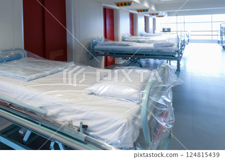 Clean hospital beds covered with film, ready for new patients. Clean hospital beds covered with film, ready for new patients. 124815439