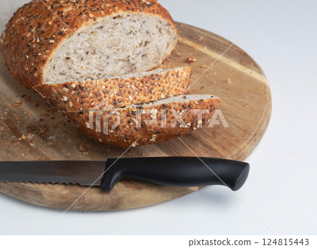 Round freshly oat baked bread sliced on a cutting board. 124815443