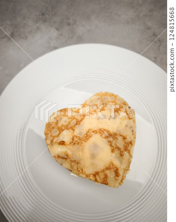 Heart shaped crepes, pancake with white yogurt sitting on white plate, symbolizing romantic morning meal with sweet culinary artistry for Mother's Day Valentines copy space 124815668