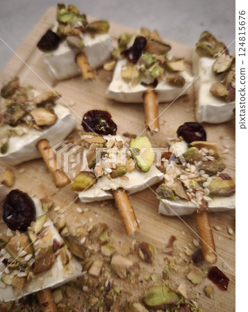 Holiday appetizer with creamy camembert, crunchy pistachios, sesame seeds, dried cranberries atop golden breadsticks. Ideal for parties, buffets, and stylish aperitifs Holiday appetizer with creamy camembert, crunchy pistachios, sesame seeds, dried cranberries atop golden breadsticks. Ideal for parties, buffets, and stylish aperitifs 124815676