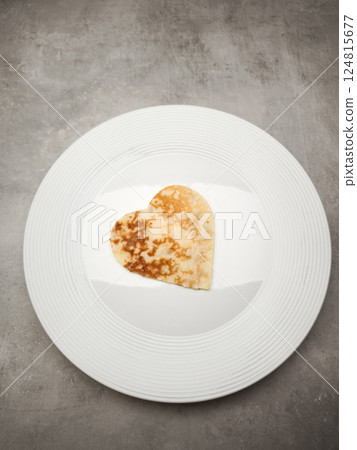 Delicious heart shaped crepe, pancake is served on a stylish white plate, creating a simple yet appealing culinary presentation for Mother's Day Valentines copy space Delicious heart shaped crepe, pancake is served on a stylish white plate, creating a simple yet appealing culinary presentation for Mother's Day Valentines copy space 124815677