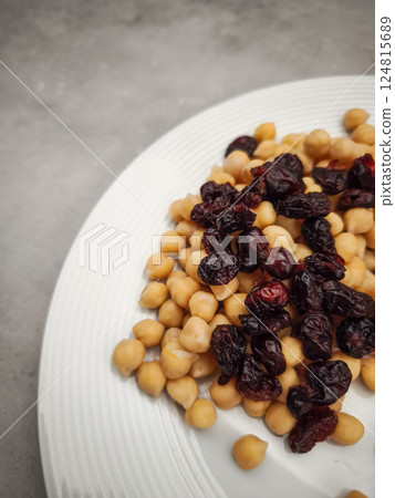 Chickpeas scattered with dried cranberries, presenting vibrant color contrast and healthy wholesome snacking on minimalist white plate healthy dinner for Galentines day 124815689