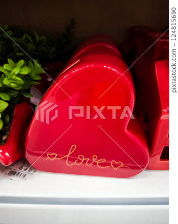 Red ceramic heart bearing golden love lettering, symbolizing romantic emotion and tender connection Valentines Day 124815690