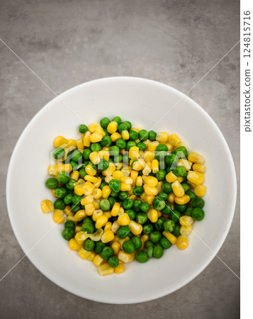 Small white ceramic bowl containing steamed green peas and golden corn kernels, resting on neutral grey surface copy space Galentines day Small white ceramic bowl containing steamed green peas and golden corn kernels, resting on neutral grey surface copy space Galentines day 124815716