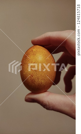 Golden onion skin easter egg resting softly in hand, revealing delicate patterns from natural dyeing process copy space 124815718