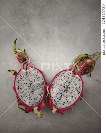 Halved dragon fruit revealing bright pink flesh, black seeds against neutral gray backdrop copy space health and wellness Halved dragon fruit revealing bright pink flesh, black seeds against neutral gray backdrop copy space health and wellness 124815720