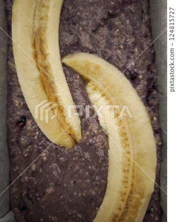 Sliced bananas nestling over blueberry oatmeal batter, promising wholesome homemade bread brimming with fruity richness for Mother's Day Valentines 124815727