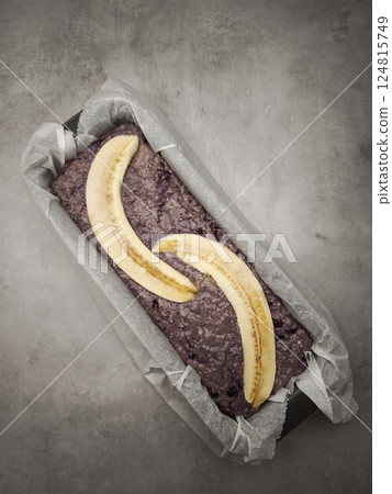 Sliced bananas topping raw blueberry banana bread batter in parchment lined loaf pan, preparing for baking for Mother's Day Valentines copy space 124815749