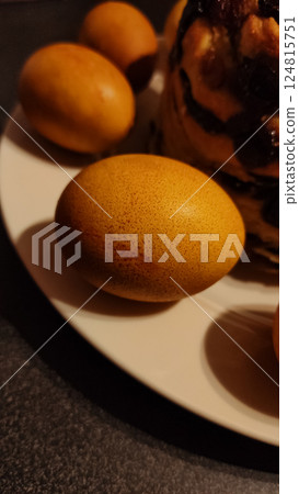 Onion golden dyed easter eggs are displayed on a white plate next to a delicious kugelhopf cake, creating a festive easter scene 124815751