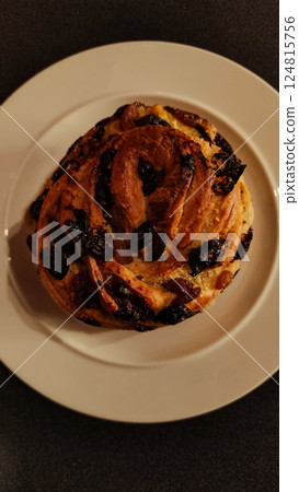 Overhead view of a freshly baked easter bread with raisins, sitting on a white plate against a dark background copy space 124815756
