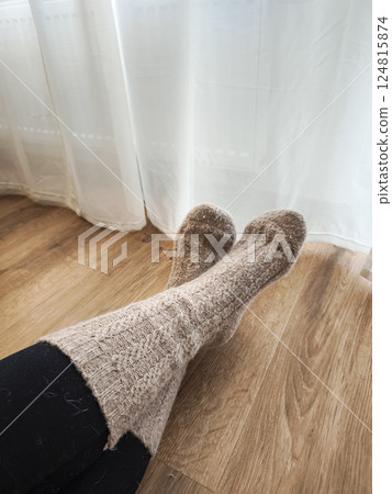 Woman relaxing in warm knitted socks near window and next to the heating, enjoying peaceful home atmosphere in prague Galentines day 124815874