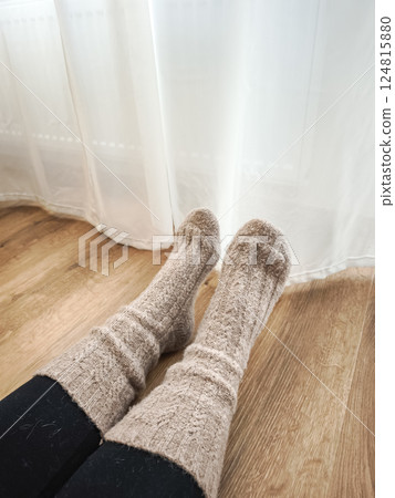 Woman resting near window and next to the heating in prague, wearing soft knitted socks, enjoying peaceful indoor atmosphere with warm light Galentines day Woman resting near window and next to the heating in prague, wearing soft knitted socks, enjoying peaceful indoor atmosphere with warm light Galentines day 124815880