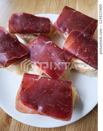 Thin slices of bresaola on bread with cheese create a simple delicious appetizer typical of northern italy and chamonix 124815900