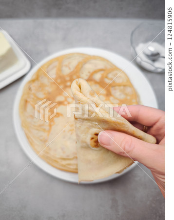 Woman holding folded crepe above plate of crepes for pancake day, shrove tuesday, maslenitsa or breakfast 124815906