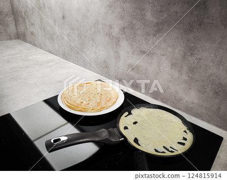Cooking crepes for shrove tuesday or maslenitsa on induction stove 124815914