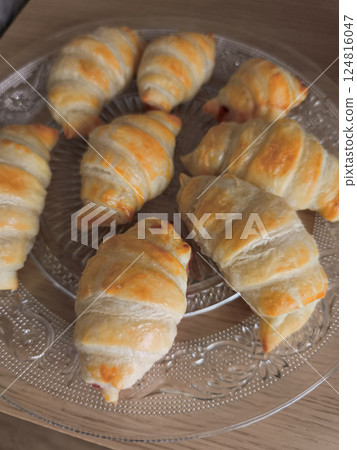 Golden croissants on glass plate, presenting romantic valentine's morning breakfast treat with delicate layers Golden croissants on glass plate, presenting romantic valentine's morning breakfast treat with delicate layers 124816047