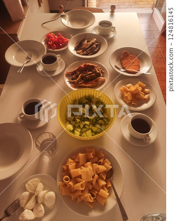 Table set for an italian lunch featuring fried fish, pasta, fresh cucumber salad, mozzarella cheese, and coffee, in bibione, italy Table set for an italian lunch featuring fried fish, pasta, fresh cucumber salad, mozzarella cheese, and coffee, in bibione, italy 124816145
