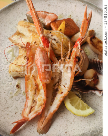 Grilled seafood medley on rustic plate, highlighting succulent shrimp, tender fish, zesty lemon wedges with mediterranean flair 124816162