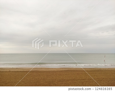 Seascape with calm waves lapping the sandy shore of bibione beach in italy under a cloudy sky Seascape with calm waves lapping the sandy shore of bibione beach in italy under a cloudy sky 124816165