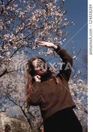 Young woman enjoying spring blossom almond tree in prague, petrin gardens Young woman enjoying spring blossom almond tree in prague, petrin gardens 124816284